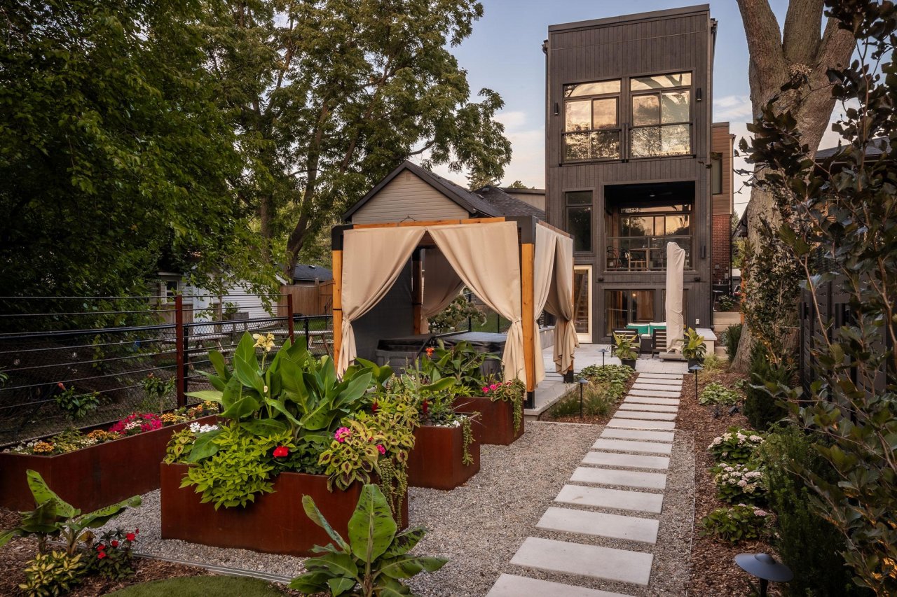Backyard landscape with a hot tub and canopy covering.