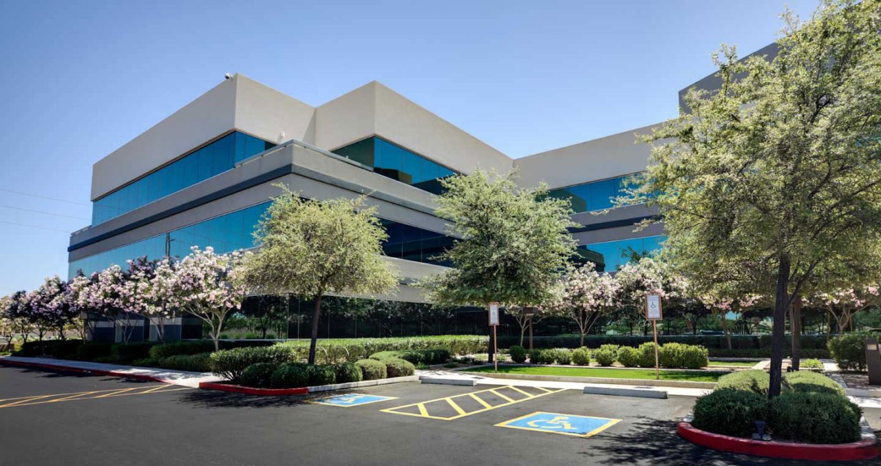 Commercial building with landscaped lawn and trees.