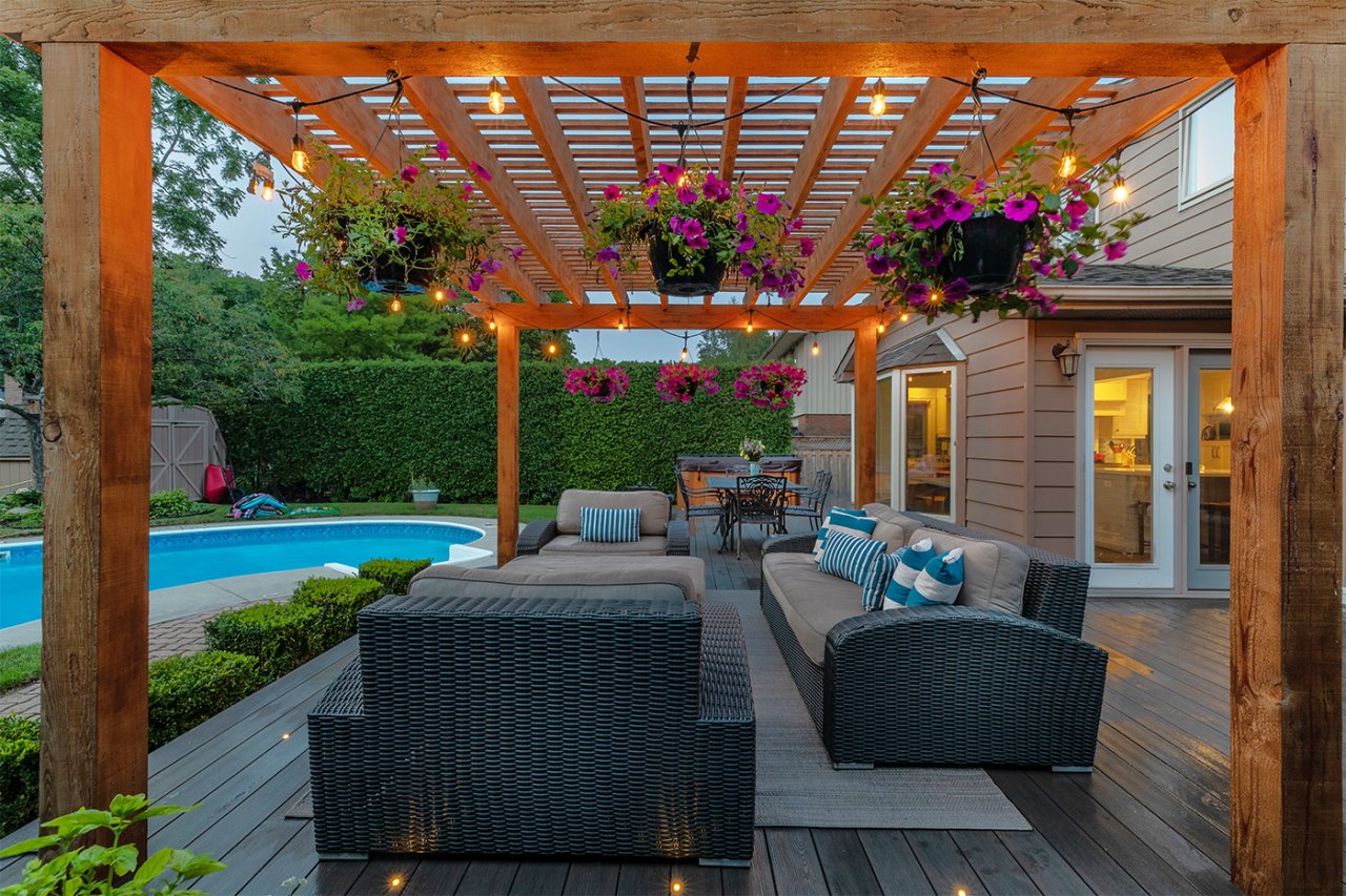 Residential backyard view from patio with a pergola, a pool, privacy hedges and a shed